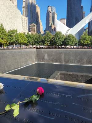 A rose on an engraved name panel beside a reflecting pool at the 9/11 Memorial in New York City.